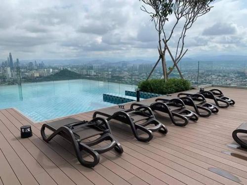 a row of chaise lounges on the edge of a swimming pool at EkoCheras Residences Van Gogh theme design with MRT Cheras in Kuala Lumpur