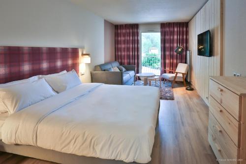 a bedroom with a large bed and a living room at Hôtel Le Refuge des Sources in Digne-les-Bains