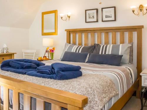 a bedroom with a wooden bed with blue pillows at Whitestones Cottage in Caister-on-Sea