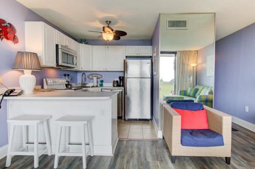 a kitchen with a counter and chairs and a refrigerator at 0102 Beach It by Atlantic Towers in Carolina Beach