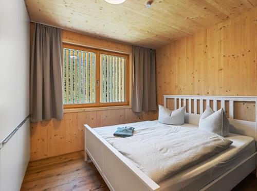 een slaapkamer met een groot bed in een houten kamer bij Neues Wood Design Apartment im Herzen des Bregenzerwalds in Mellau