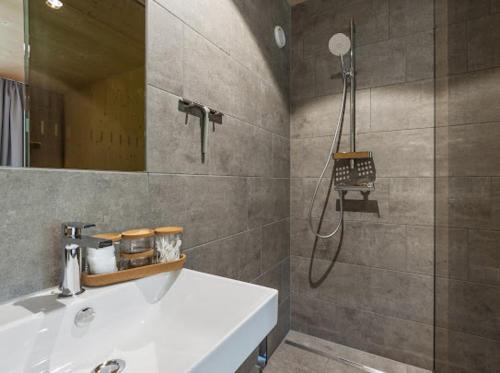 a bathroom with a shower and a white sink at Neues Wood Design Apartment im Herzen des Bregenzerwalds in Mellau