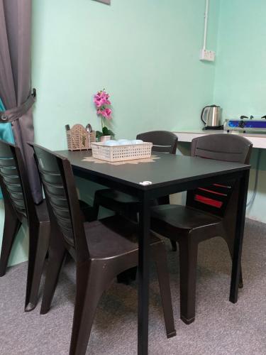 una mesa de comedor negra con sillas y flores en Mini Homestay Arifz Zai, en Batu Kurau