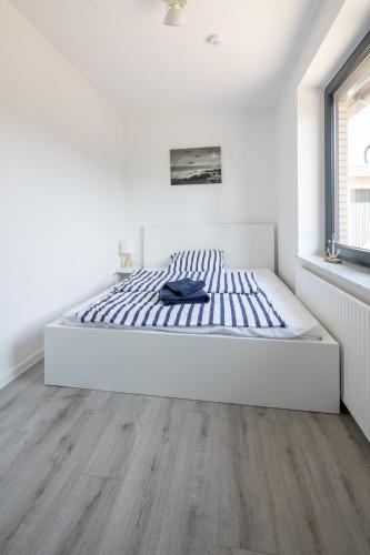 a bed in a white room with a wooden floor at Ferienwohnung Seebär in Wangerland