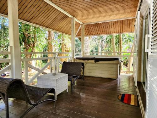 un porche grillagé avec des chaises et une baignoire dans l'établissement EVASION Bungalow d'Antan Spa, à Sarraméa