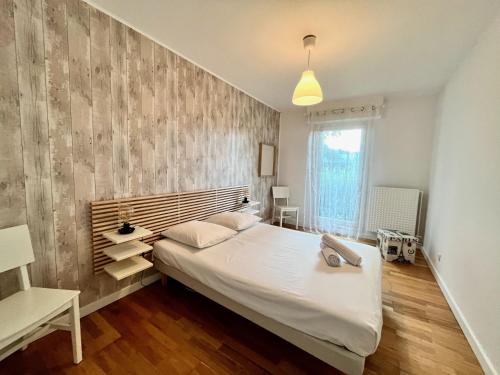 - une chambre avec un grand lit blanc et une tête de lit en bois dans l'établissement L'ALTAIR - P4 à 2 pas du Pasino, 10 min des plages, clim, parking, à La Grande Motte