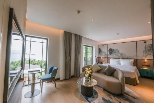 a hotel room with a bed and a couch and a table at Cat Ba Island Resort & Spa in Cat Ba