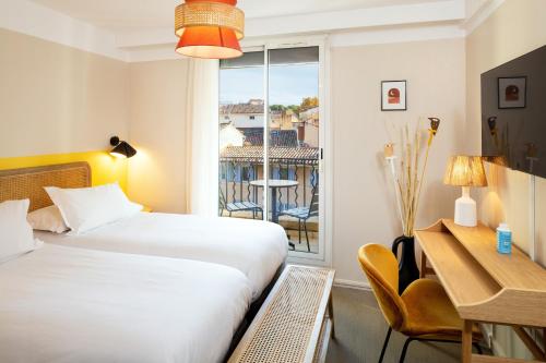 a hotel room with a bed and a desk and a window at Hôtel Escaletto in Aix-en-Provence