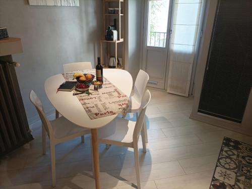 a white dining room table with chairs and a bottle of wine at La contrada in Cuneo