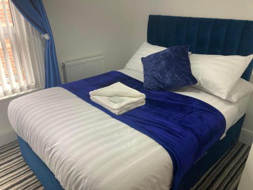 a bed with a blue and white blanket and pillows at The New Astoria Hotel in Blackpool