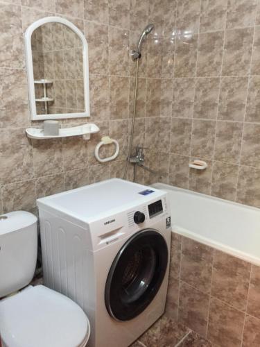 a bathroom with a washing machine and a toilet at Однокомнатная квартира посуточно in Balqash