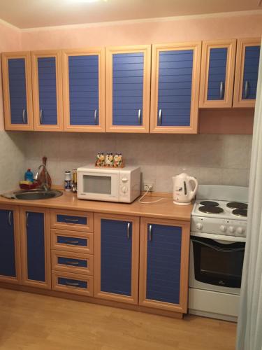 a kitchen with wooden cabinets and a microwave and a stove at Однокомнатная квартира посуточно in Balqash