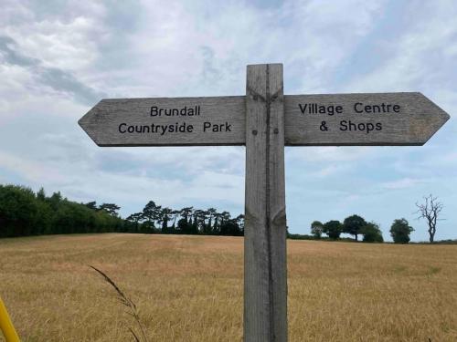 um sinal de rua de madeira no meio de um campo em Relaxing retreat near Norfolk Broads em Norwich