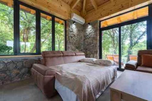 ein Schlafzimmer mit einem Bett, einem Sofa und Fenstern in der Unterkunft Rijeka Zeta, Podgorica in Podgorica
