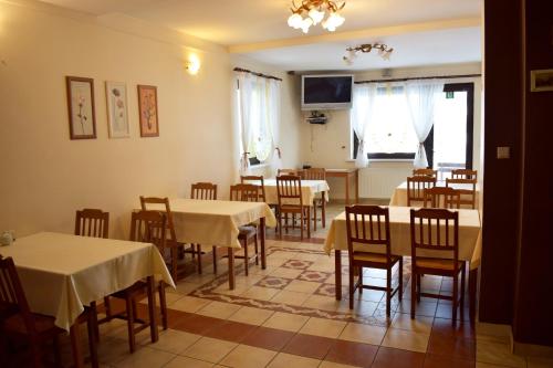 uma sala de jantar com mesas e cadeiras e uma televisão em Fazolandia em Zwardoń