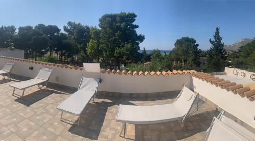 a patio with white chairs and a fence at L'oasi Una Pineta Sul Mare in Custonaci