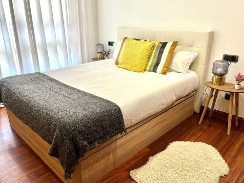 een slaapkamer met een bed met een geel kussen en een tapijt bij Apartamento Olívico con Parking in Vigo