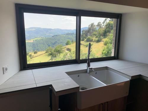 a kitchen with a sink and a large window at Les chambres de la Bastide in Saint-Sauveur-de-Montagut