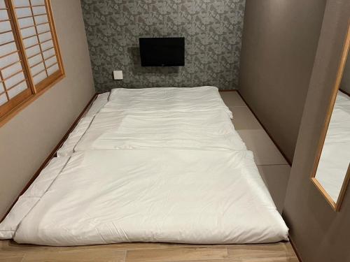 a large white bed in a room with a tv at Asagaya House in Tokyo