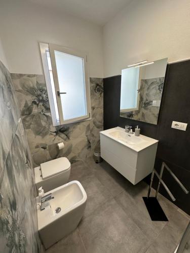 a bathroom with a sink and a toilet and a mirror at Artemisia Home in Olbia