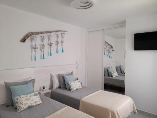 een slaapkamer met 2 bedden, een tv en een spiegel bij Bungalow La Palmera - 2 bedroom - PLAYA ROCA residence sea front access - Pool View - Free AC - Wifi in Costa Teguise