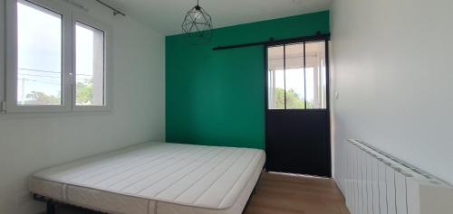 a bedroom with a white bed and a green wall at Résidence Salamandre - Maison Bois Cosy Calme avec parking pour 4 à 10 pers idéal couples et familles à 500m de la plage à Saint-Marc-sur-mer in Saint-Nazaire