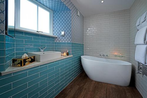 baño de azulejos azules con bañera y lavamanos en Monks Ballyvaughan, en Ballyvaughan