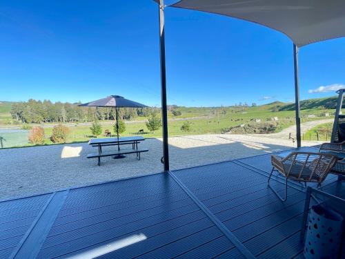 a deck with a picnic table and a picnic bench at Waitomo Retreat in Hangatiki