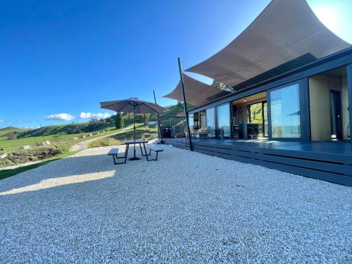 ein Gebäude mit zwei Bänken und einem Regenschirm in der Unterkunft Waitomo Retreat in Hangatiki