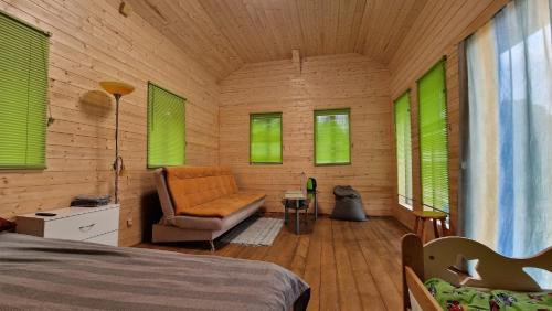 a bedroom with green windows and a bed and a chair at SP camping Spāres Prieduļi in Nīca