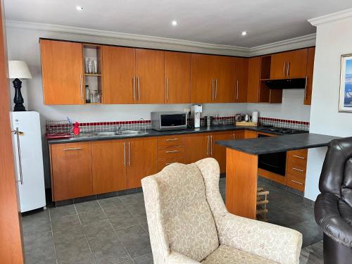 a kitchen with wooden cabinets and a chair and a counter at Dux in Montagu
