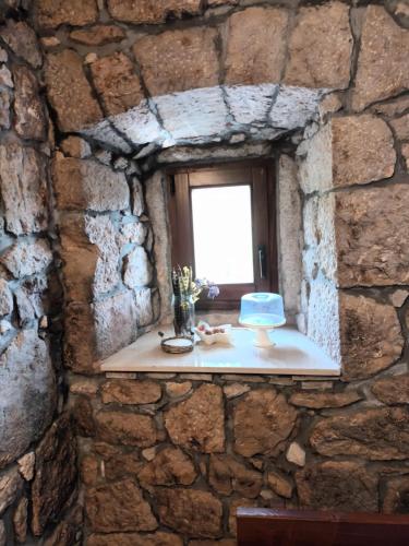 ein Fenster in einer Steinmauer mit einem Kuchen auf einem Tisch in der Unterkunft Kuća za odmor Grupković in Ploče