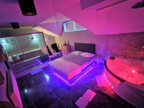 1 dormitorio con cama y bañera en una habitación con luces rosas en Guesthouse and Wellness VINEA en Spodnji Ivanjci