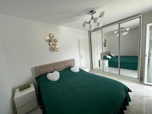 een slaapkamer met een groen bed en een spiegel bij Confortabil si modern in Boekarest