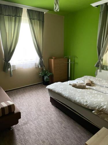 zieloną sypialnię z łóżkiem i oknem w obiekcie Vadviraghaz w mieście Palkonya