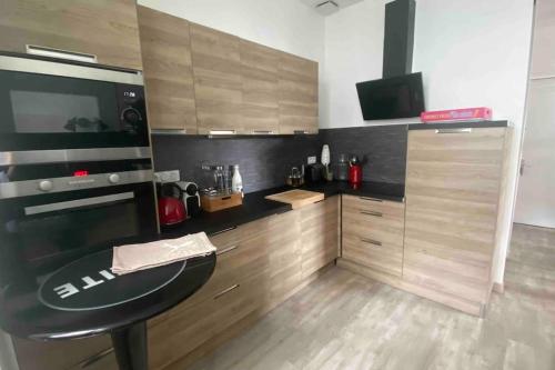 eine Küche mit einer schwarzen Arbeitsplatte und Holzschränken in der Unterkunft Appartement Dol de Bretagne centre in Dol-de-Bretagne