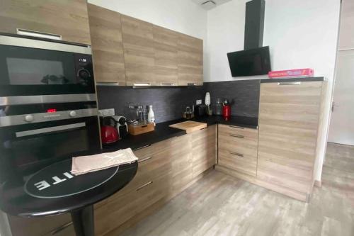 a kitchen with a black counter top and wooden cabinets at Appartement Dol de Bretagne centre in Dol-de-Bretagne