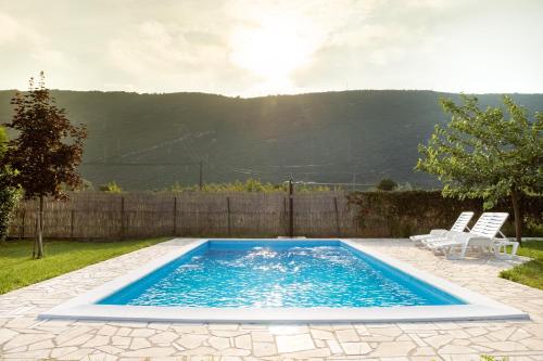 a swimming pool in a yard with two white chairs at Holiday Home Vemini in Mostar