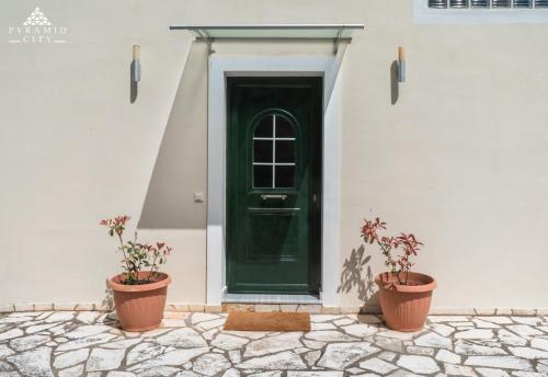 zielone drzwi na białym budynku z dwoma doniczkami w obiekcie Villa Poseidon w mieście Agios Spirydon