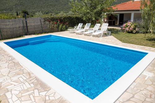 uma piscina azul com cadeiras num quintal em Holiday Home Vemini em Mostar