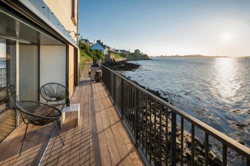 - un balcon avec deux chaises et une vue sur l'eau dans l'établissement ILE CEZON - Duplex de luxe avec magnifique vue mer, à Landéda