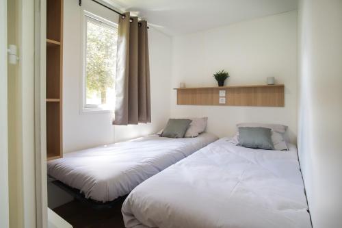 2 Betten in einem Zimmer mit Fenster in der Unterkunft Camping Le Florenville in Florenville