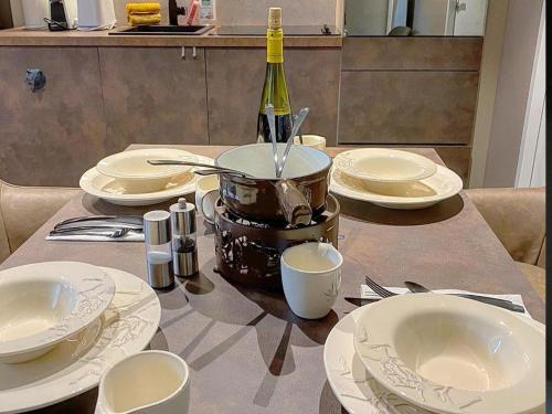 a table with white plates and a bottle of wine at Bel Air - Propriétés Mont Amour in Montriond