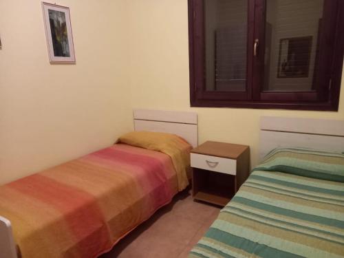 een kamer met 2 bedden, een tafel en een raam bij Villetta Casa Rosa in Castelluzzo