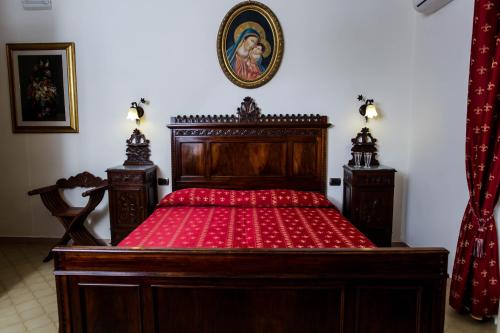 a bedroom with a wooden bed with red sheets at La Quercia Antica B&B in San Cipriano Picentino