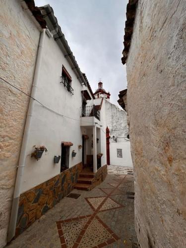 an alley with a white building with a red doorway at Casa Veracruz in Benarrabá