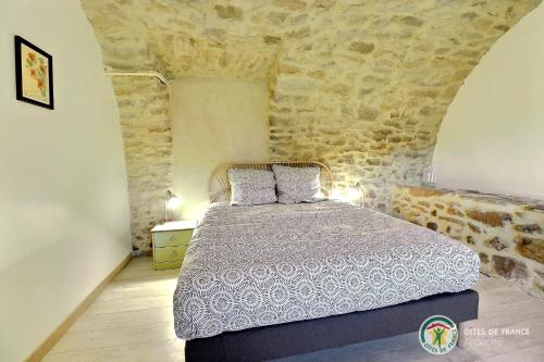 une chambre avec un lit et un mur en pierre dans l'établissement Le Bonlieu des Volets rouges, à Saint-Sauveur-de-Cruzières