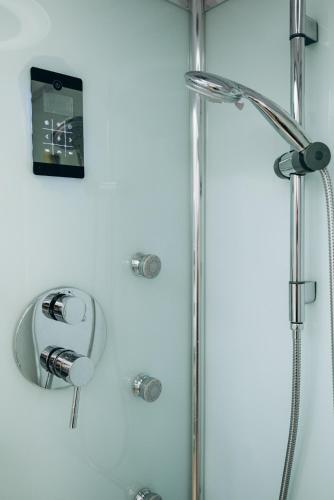 a shower in a bathroom with a clock on the wall at Kalos Apartments Catania in Catania