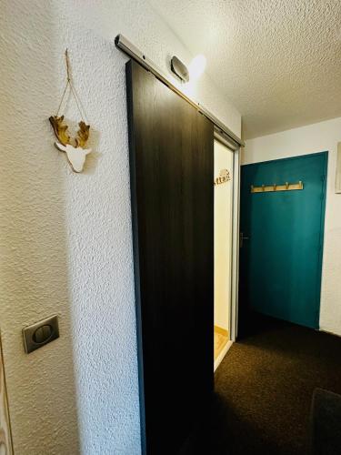 un couloir avec une porte noire et un mur bleu dans l'établissement L'AnsloBoys Montagne J4, à Les Deux Alpes