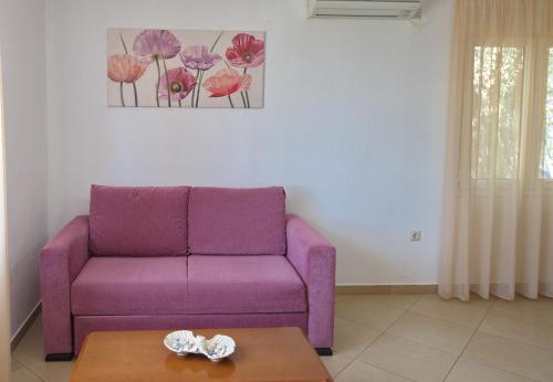 a purple couch in a living room with a table at Myrtilo cottage in Votsi